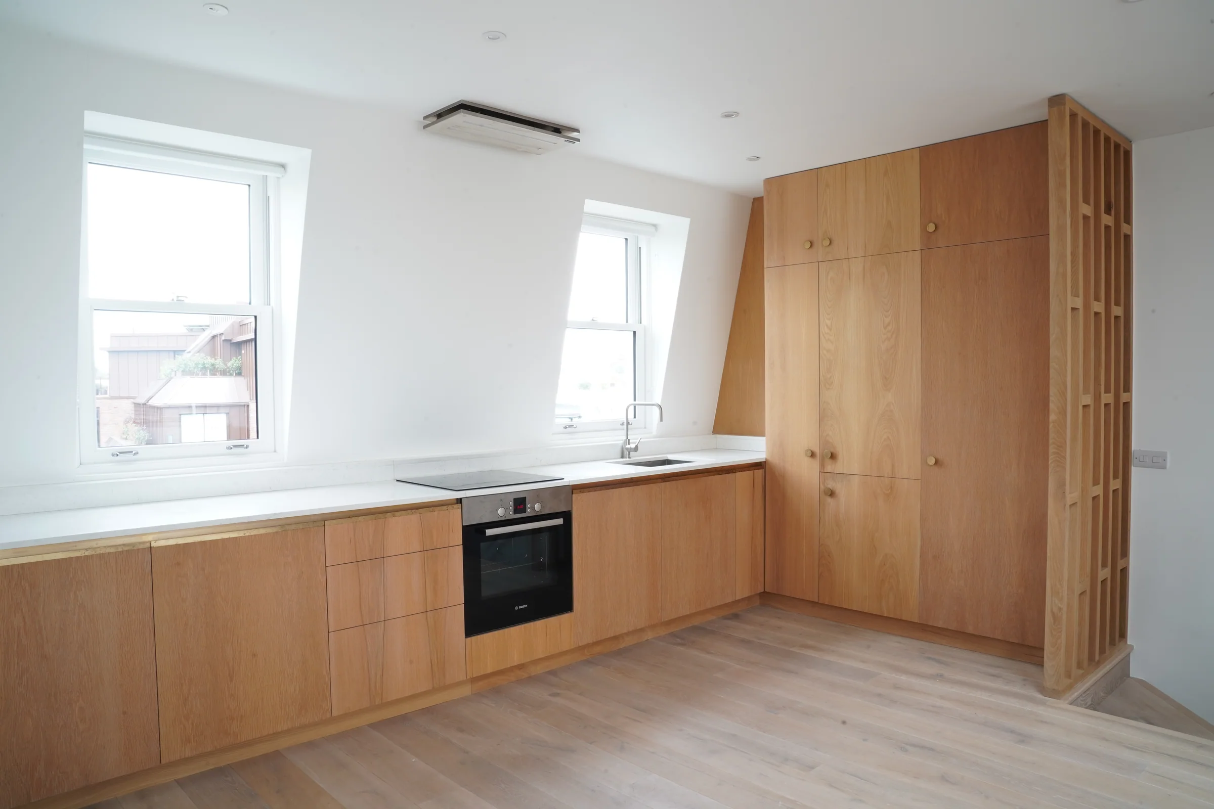 Timber-fronted penthouse kitchen beneath the sloping roof.