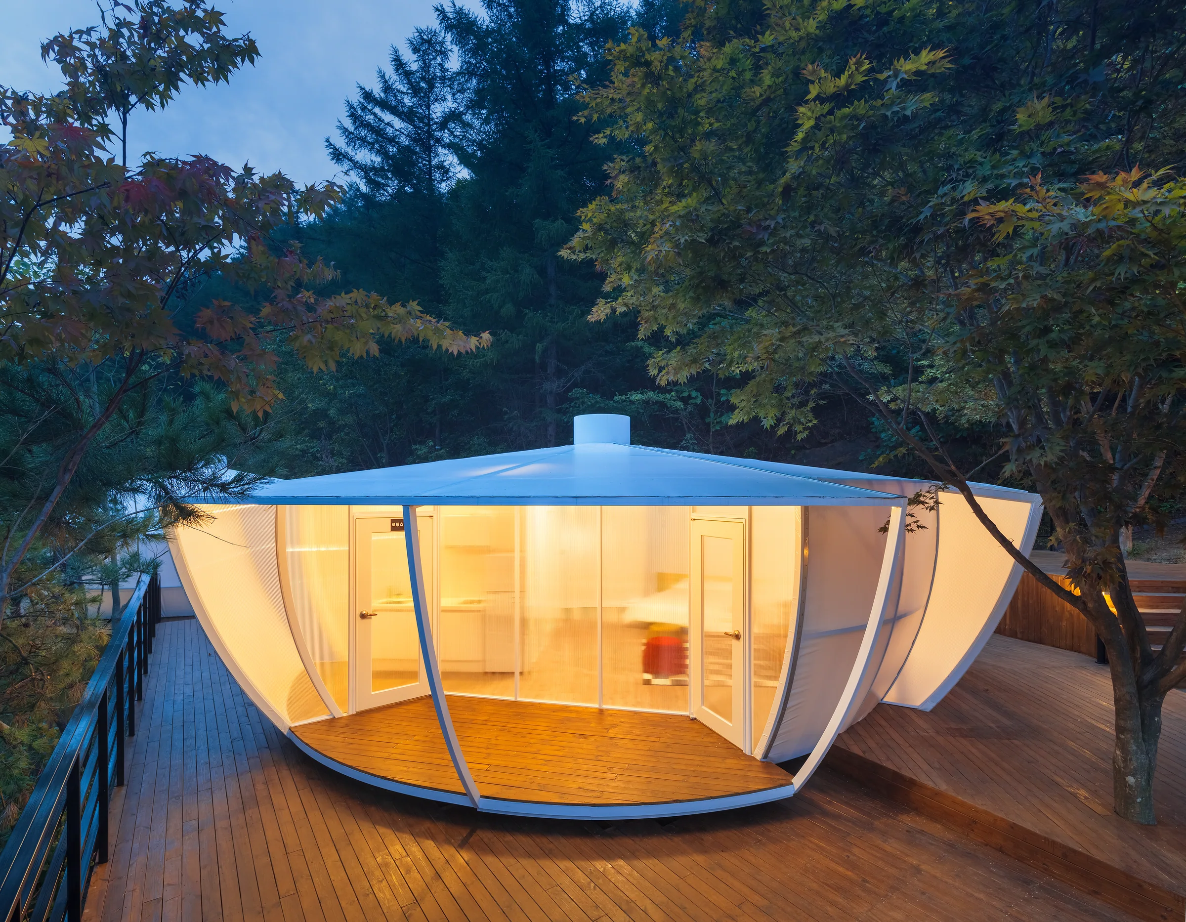 Front view of the circular glamping pavilion and its glazed entrance.
