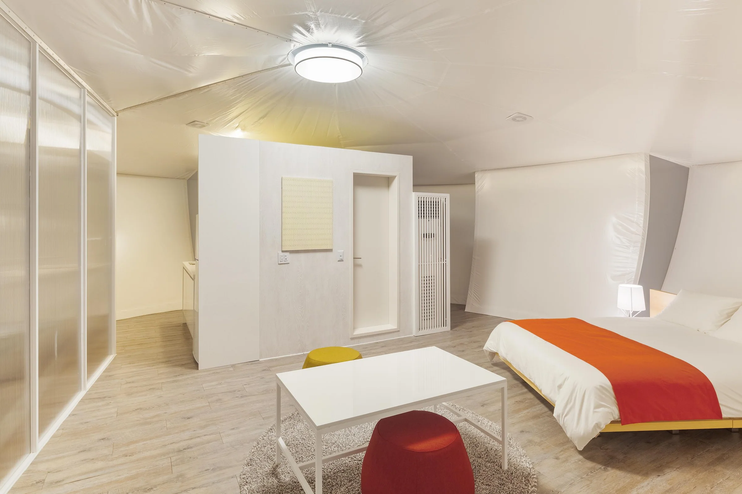 Interior of the glamping pavilion with radial ceiling structure and a raised bed.