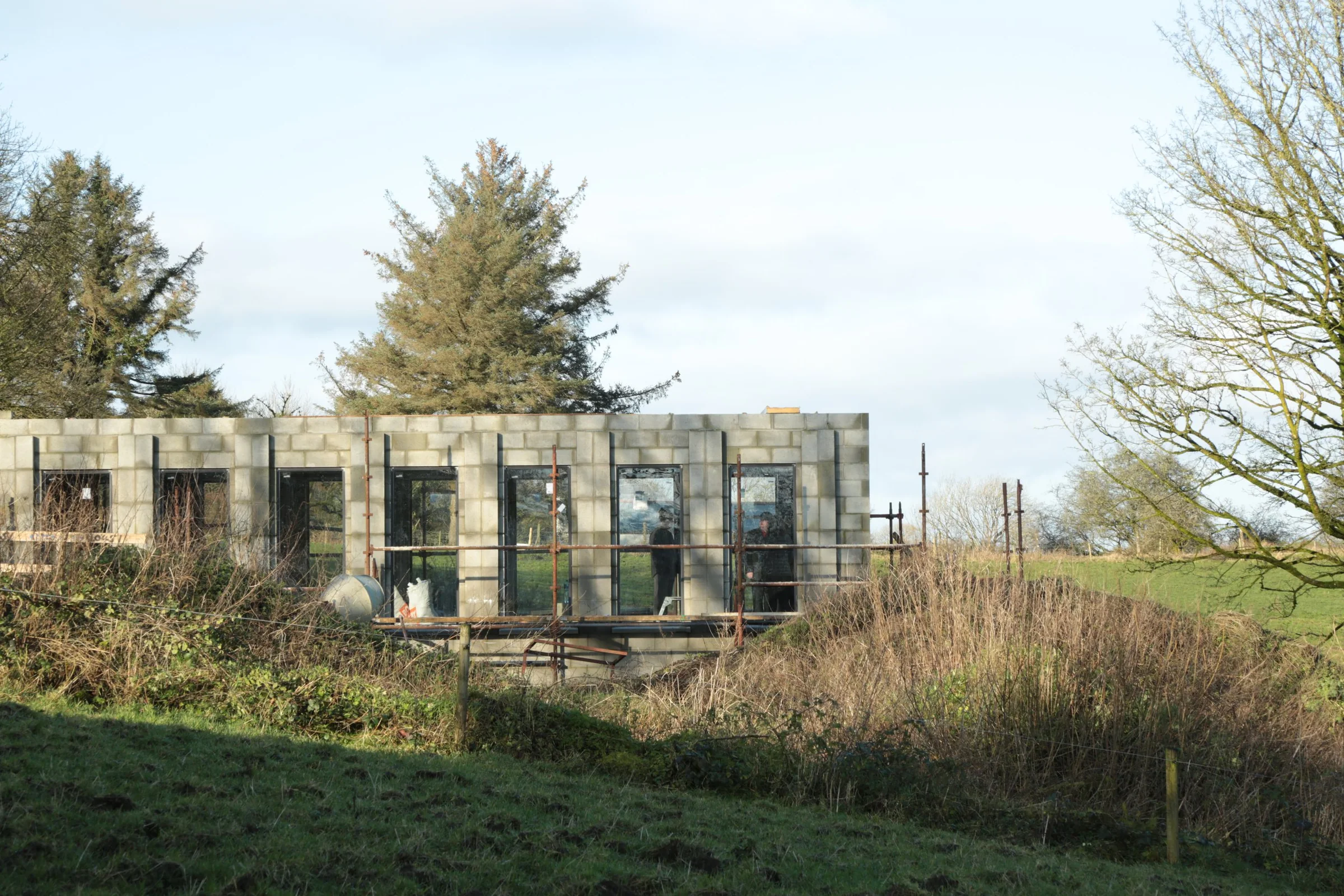 Construction-stage view of Larganboy House among mature trees.
