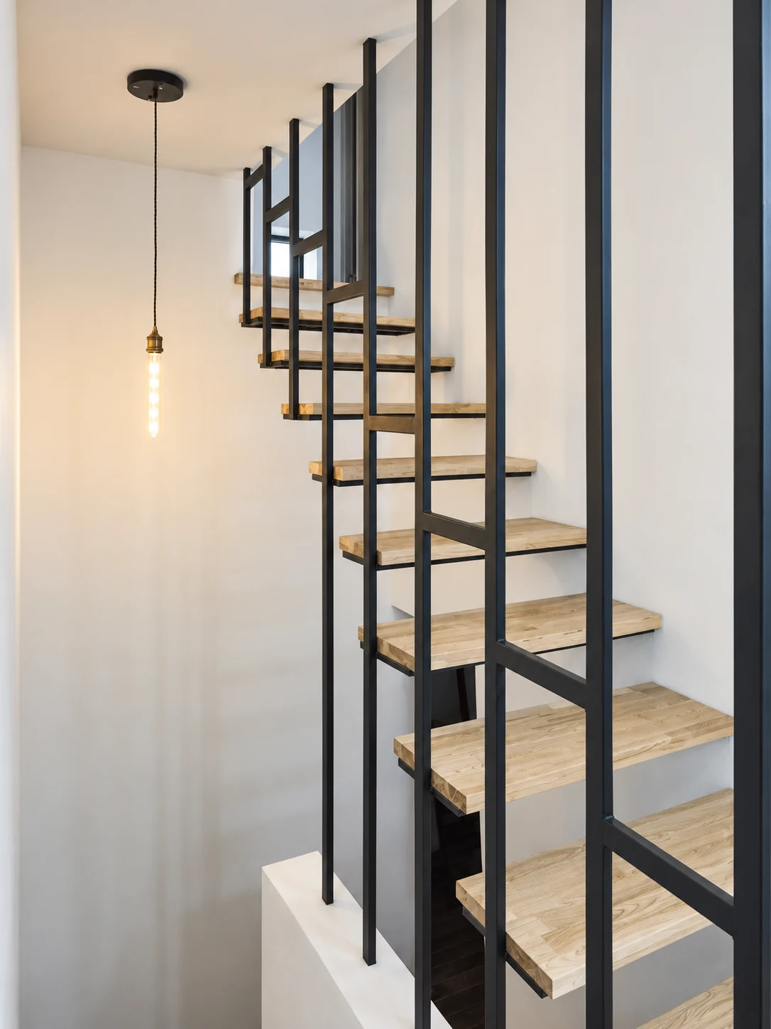 Close view of open timber stair treads held within vertical dark steel members.