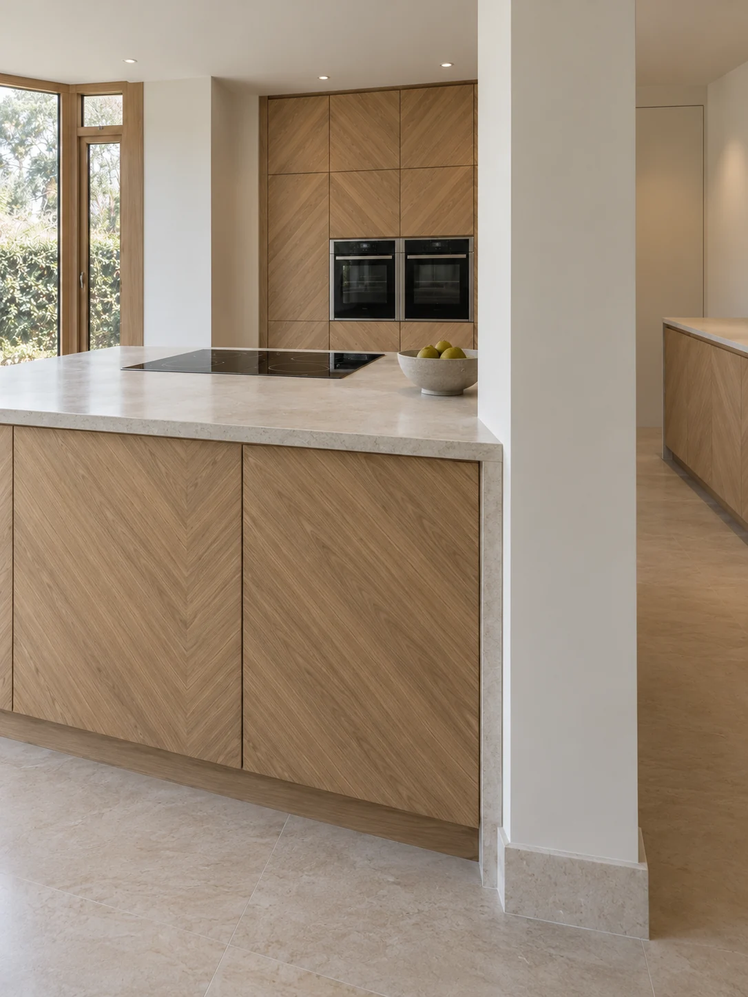 Detail of the chevron-patterned island front and pale worktop beside the structural pier.