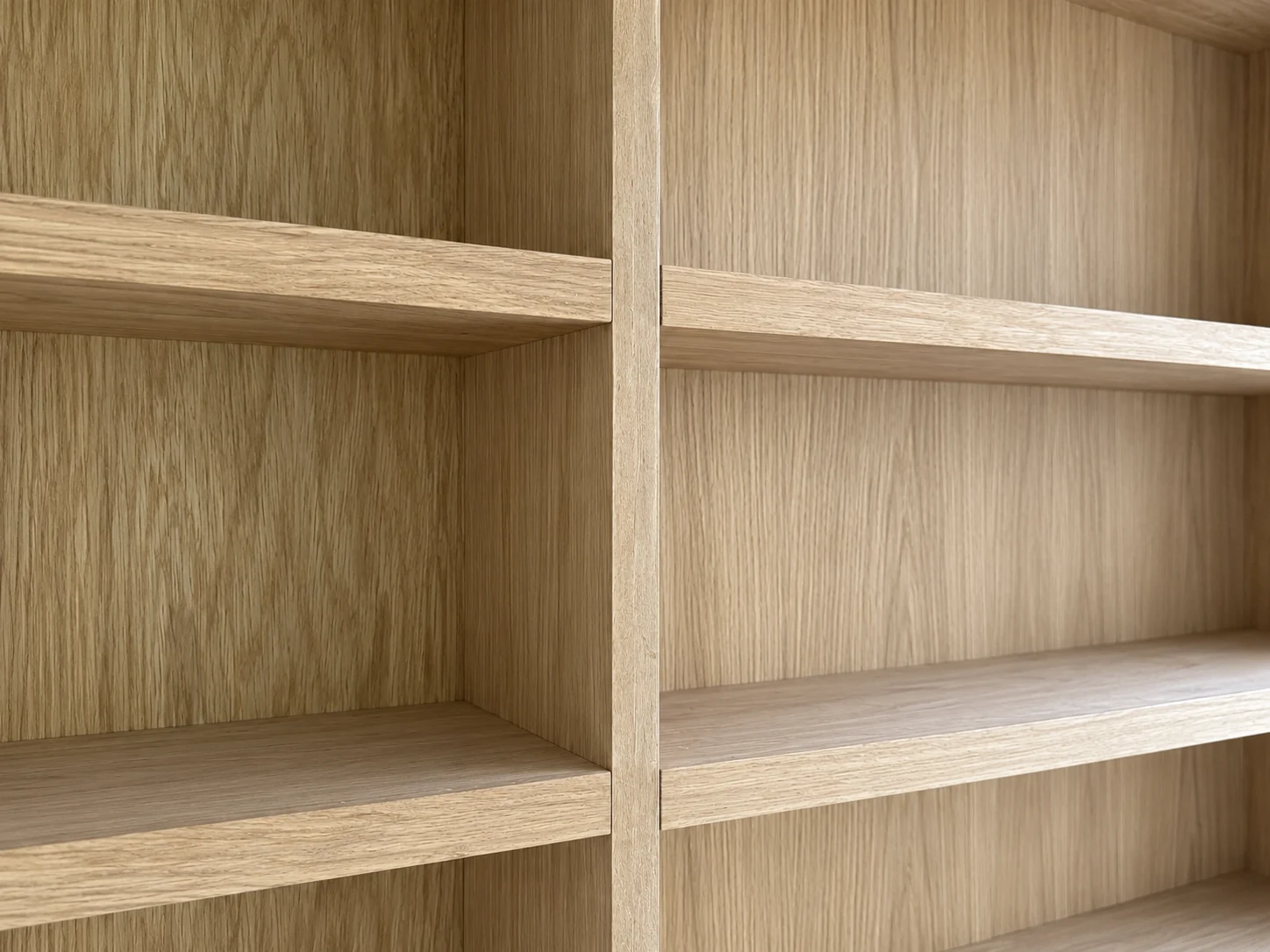 Detail of oak shelving with a central upright and offset horizontal shelves.