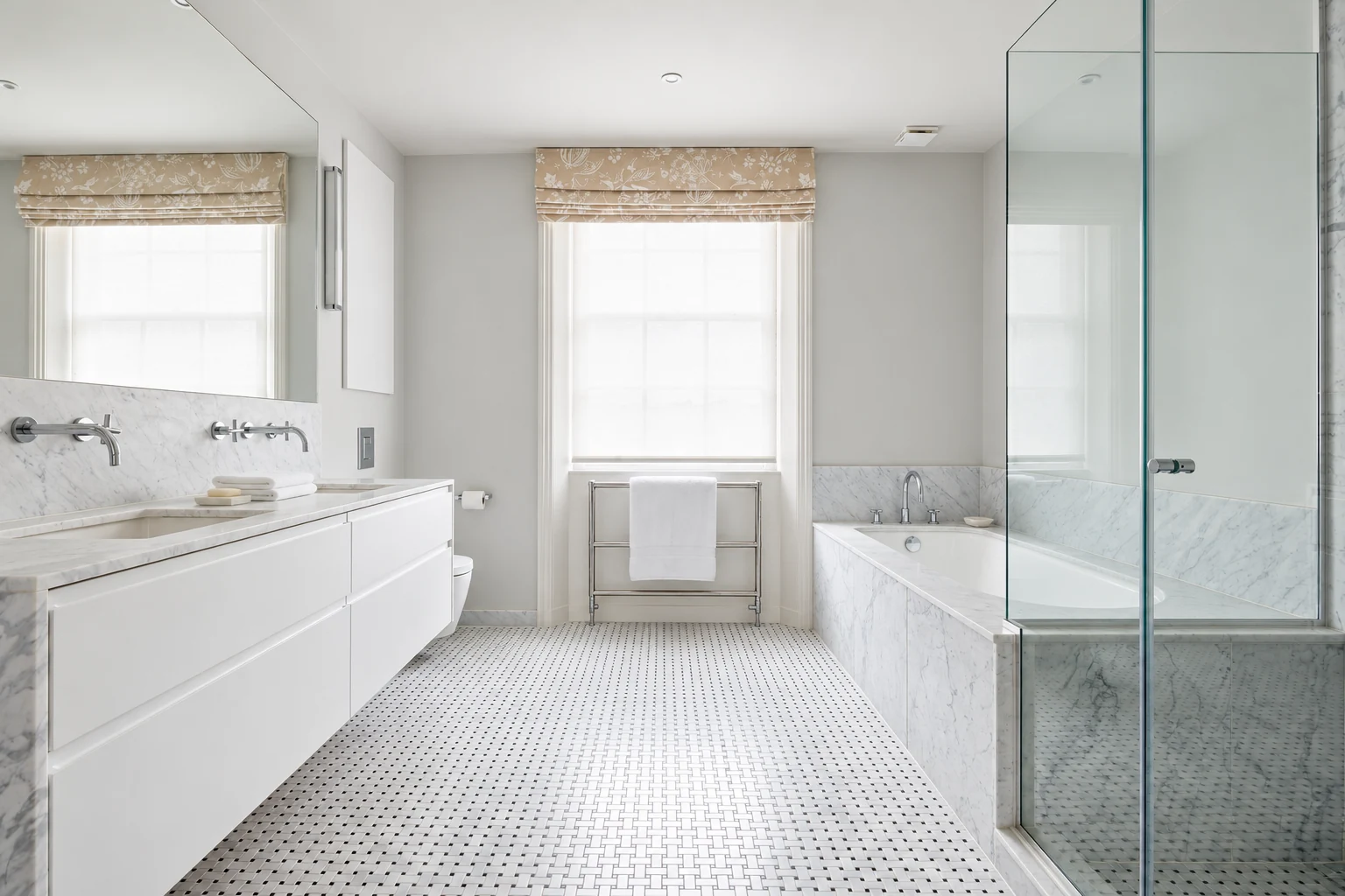 Bathroom with double vanity, marble bath and wall lining, basketweave mosaic floor and glass shower screen.