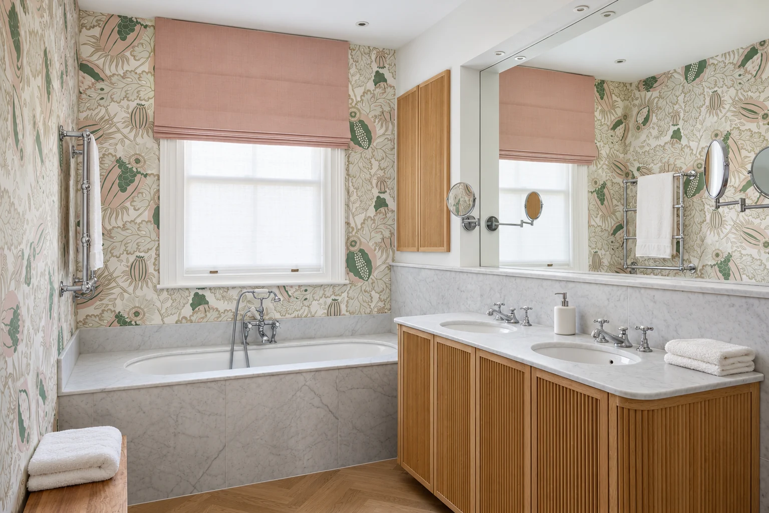 Botanical wall covering above a marble bath and a curved double vanity with oak slats.