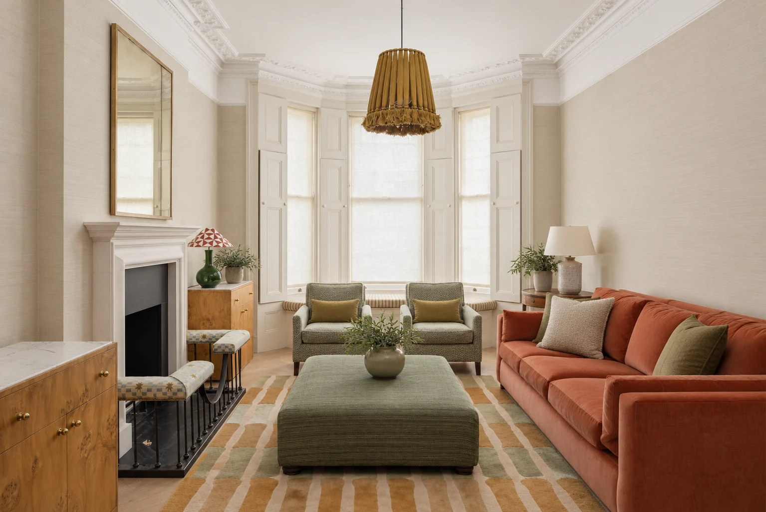 Reception with a three-part bay, white cornice, rust sofa, sage chairs and green ottoman.